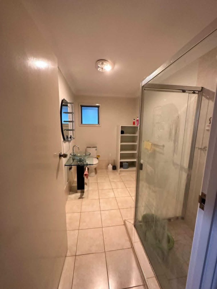 Bathroom before renovation with a framed shower screen and original wall tiles