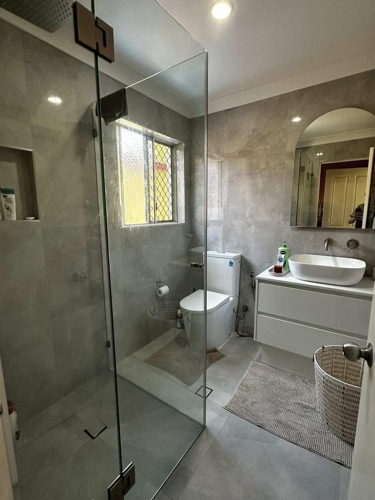 Completed bathroom with an arched mirror, vessel basin and stone-look floor and wall tiles