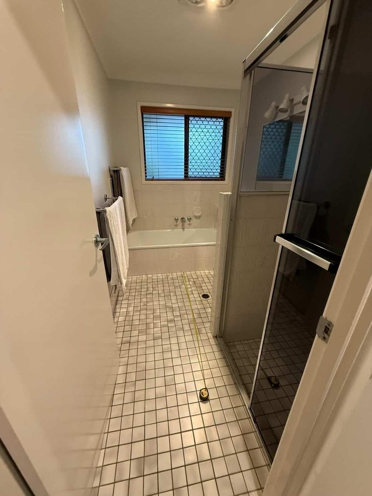 Second bathroom before renovation with an inset bath and small mosaic floor tiles
