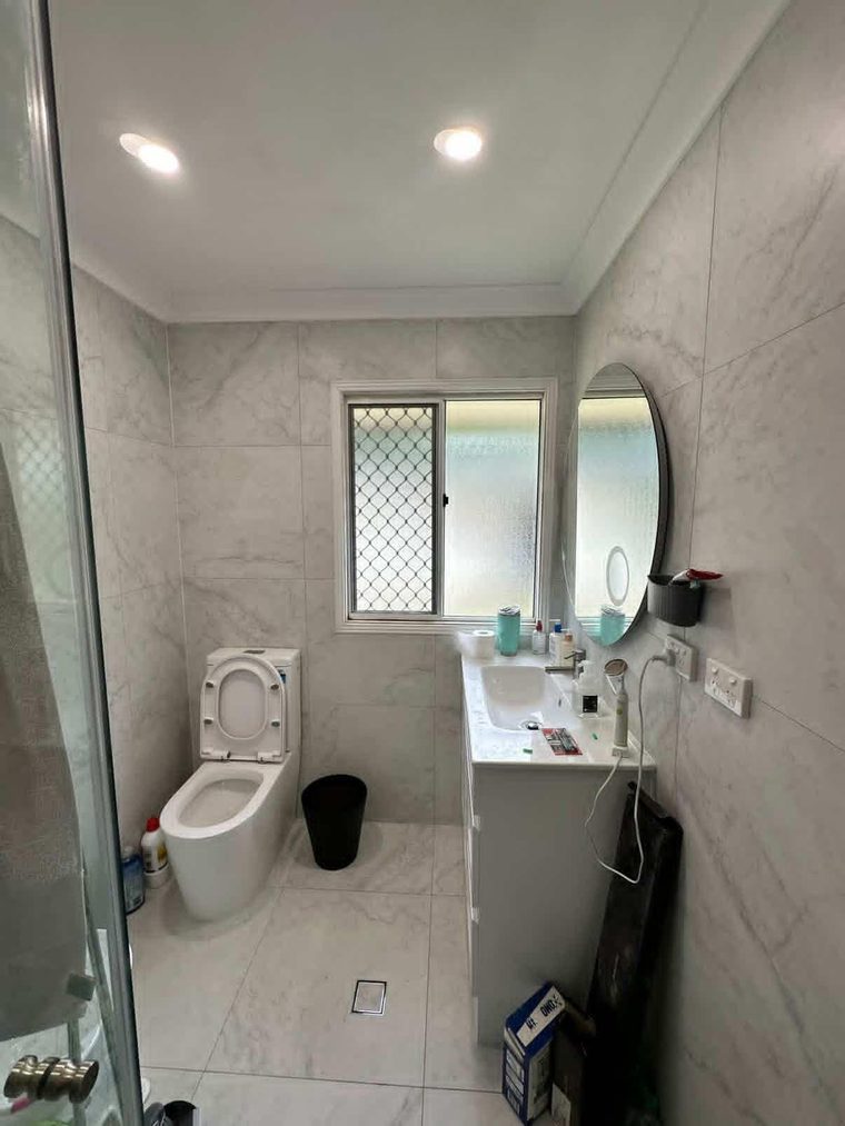 Completed bathroom with marble-look wall tiles, a wall-hung vanity and an oval mirror