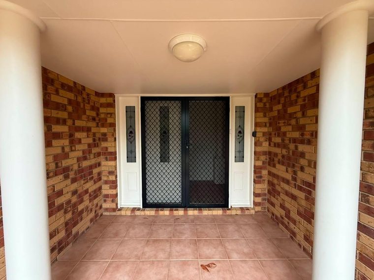 Entry hallway before renovation with exposed brick walls and dated floor tiles