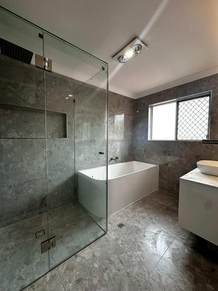 Completed HEPH Reno bathroom with stone-look tiling, a freestanding bath and a frameless glass shower