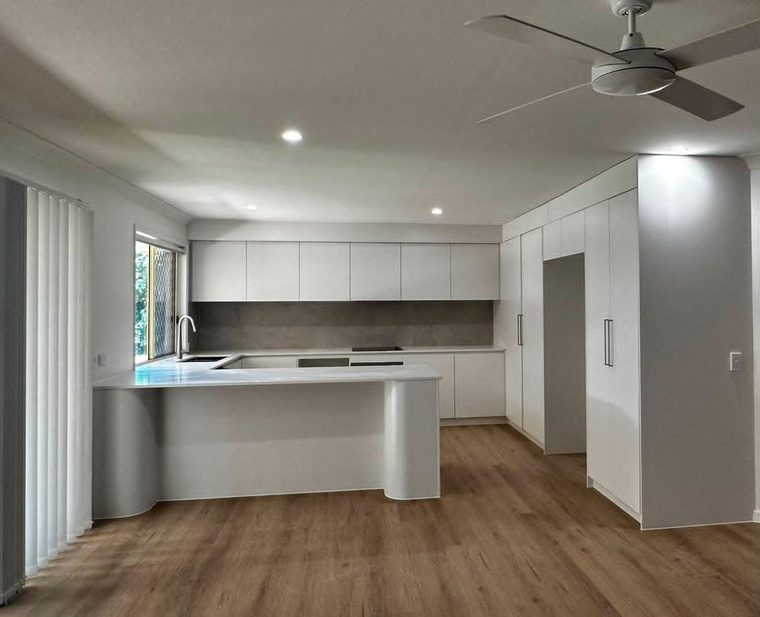 Same kitchen completed with new white joinery, stone benchtops and timber-look flooring