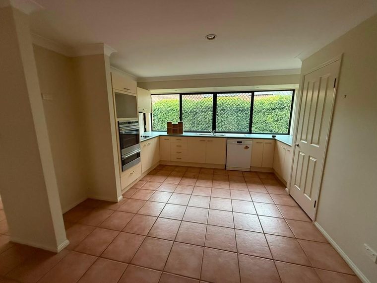 Kitchen before renovation with dated laminate cabinetry and terracotta floor tiles