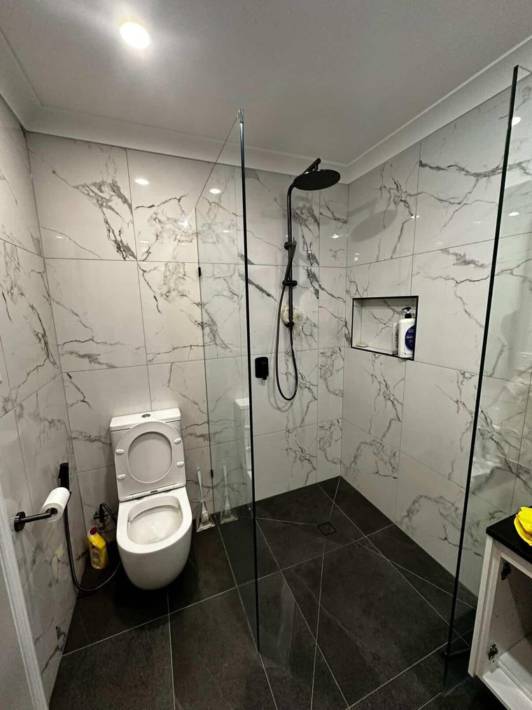 Walk-in shower with a tiled recessed niche, matte black tapware and marble-look tiling
