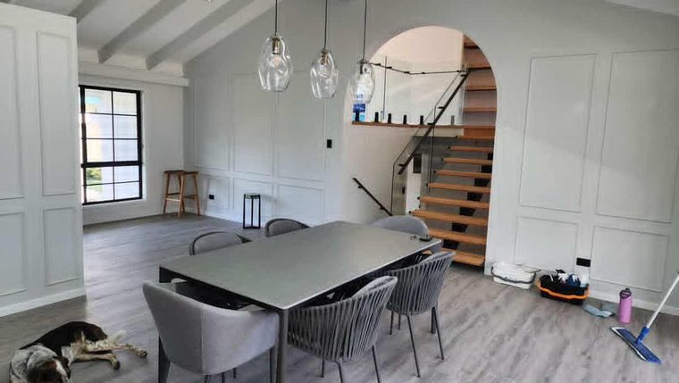 Renovated dining room with panelled walls, exposed beams, hybrid flooring and a timber staircase