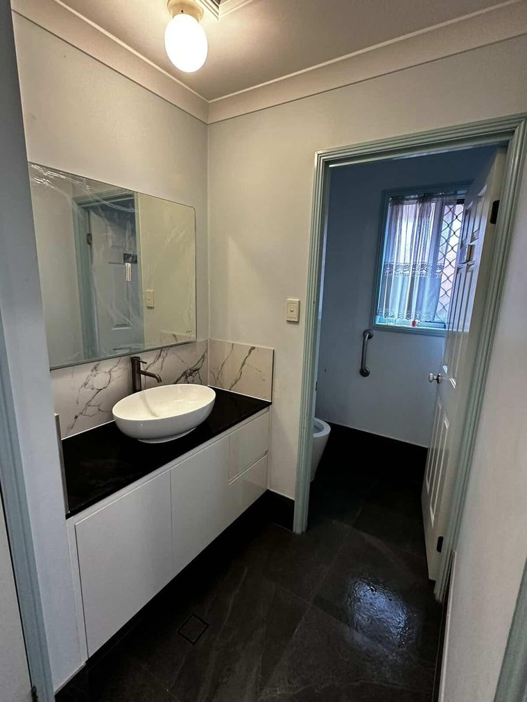 Wall-hung vanity with a stone top, vessel basin and charcoal tiled floor